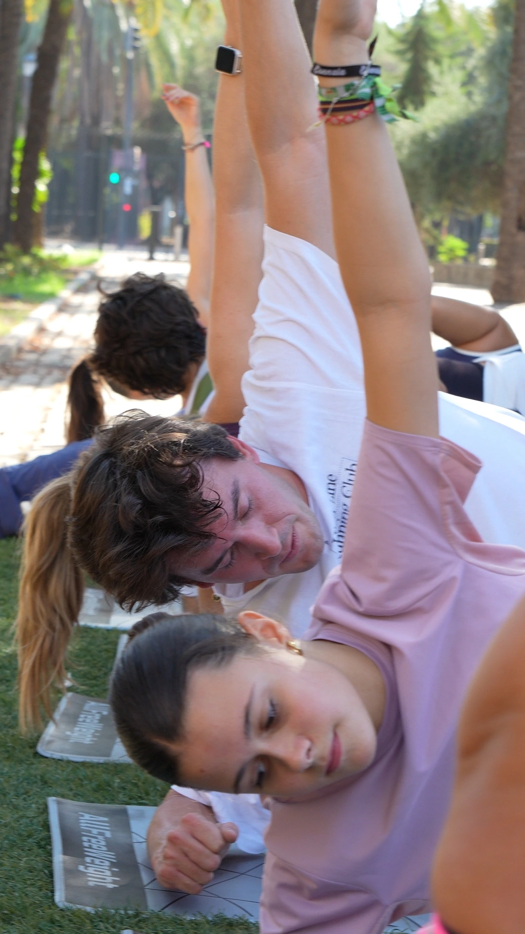 Participantes estiran hacia un lado con un brazo levantado al aire libre.